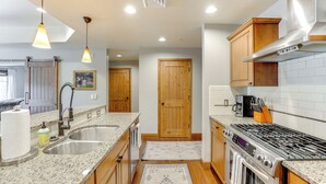 A modern kitchen with granite countertops, stainless steel appliances, wooden cabinets, and pendant lighting. - Half-Mi to Payette Lake: Dtwn McCall Condo! (McCall)