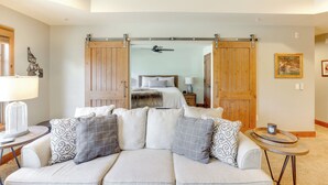 A modern living room with a sofa, a coffee table, and a large sliding door leading to a bedroom. - Half-Mi to Payette Lake: Dtwn McCall Condo! (McCall)