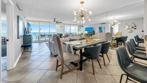 Uma sala de estar ampla com uma grande mesa de jantar, assentos confortáveis e vista para o oceano.