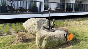 Een modern gebouw met een balkon, een metalen sculptuur en een grote rots.
