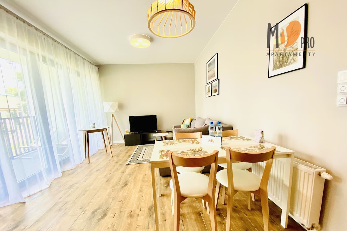 Una sala de estar bien iluminada, con comedor, televisor y radiador.