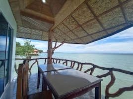 A wooden deck with a table and chairs, overlooking a body of water.