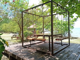 Una terraza de madera con un columpio, una mesa de picnic y bancos.