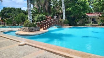 Una piscina con un ponte di legno e palme.