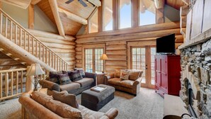 A log cabin interior with a wooden staircase, a ceiling fan, a fireplace, and a television. - Mountain View Log Home I Hot Tub I Arcades I Great Views I Sauna I Discounted Attractions (Fraser)