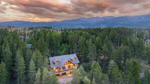 A large log cabin with a balcony, surrounded by dense forest and mountains in the background. - Mountain View Log Home I Hot Tub I Arcades I Great Views I Sauna I Discounted Attractions (Fraser)