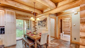 A wooden cabin interior with a dining area featuring a wooden table, chairs, and a chandelier. - Mountain View Log Home I Hot Tub I Arcades I Great Views I Sauna I Discounted Attractions (Fraser)