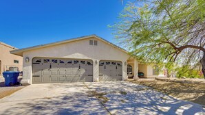 A two-car garage attached to a house with a concrete driveway and a tree casting shadows. - Lake Havasu Getaway w/ Pool, Hot Tub & Game Room (Lake Havasu City)