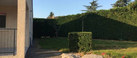 Un bâtiment avec une allée en gravier, une petite haie et un mur en pierres.