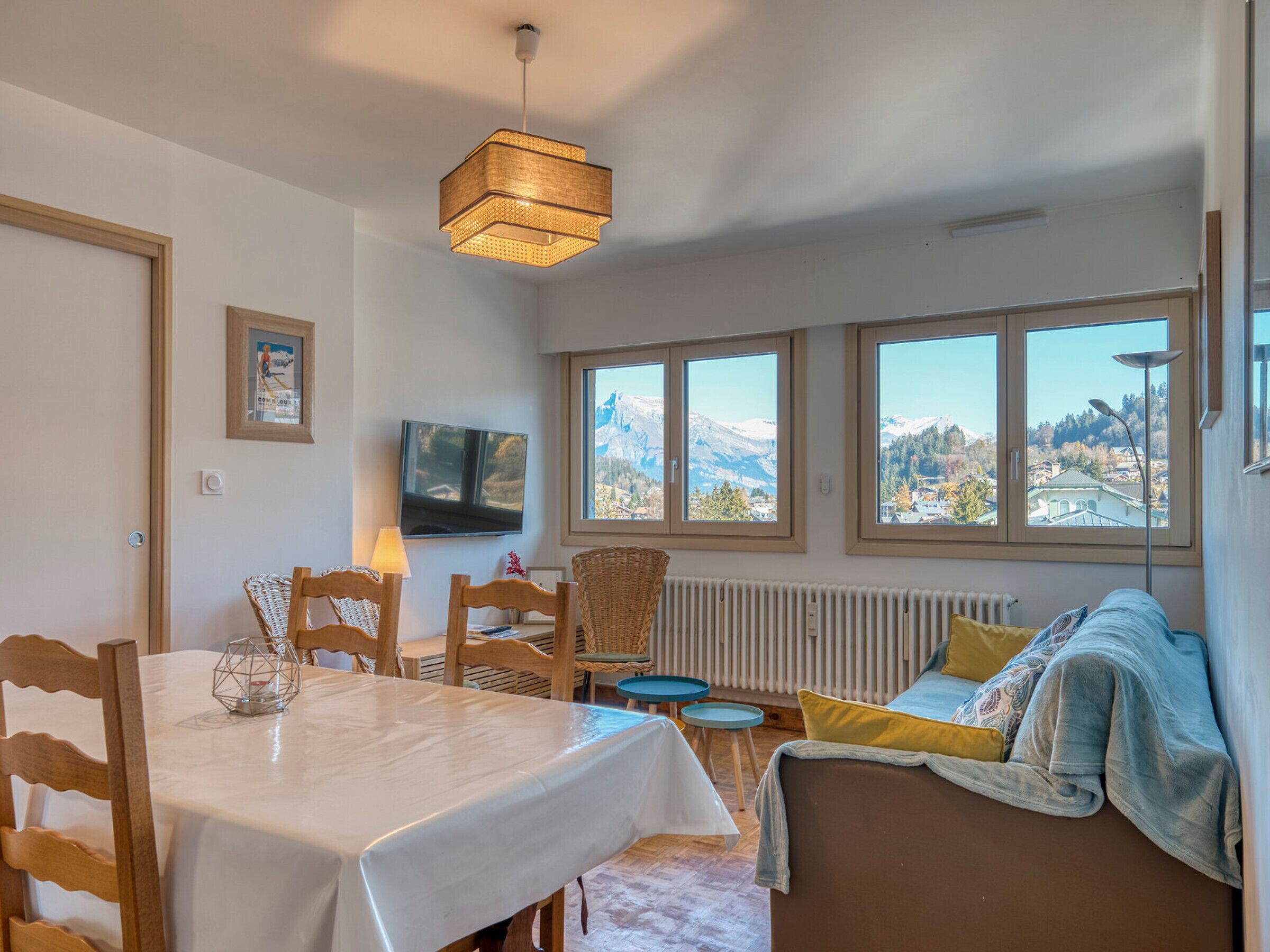 Un espace repas comprenant une table, des chaises et offrant une vue sur les montagnes grâce à de grandes fenêtres.