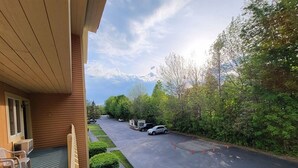 A hotel with a covered outdoor seating area, a parking lot, and a view of the surrounding greenery. - Perfect vacation getaway. #237 (Lincoln)