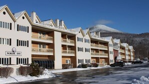 A Nordic Inn hotel with multiple balconies, a snow-covered mountain in the background, and a clear sky. - Perfect vacation getaway. #237 (Lincoln)