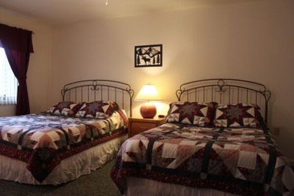 Een kamer met twee eenpersoonsbedden, elk voorzien van een gewatteerde sprei en kussens met sterrenprint. Daarboven hangt een schilderij aan de muur en op het nachtkastje staat een lamp.