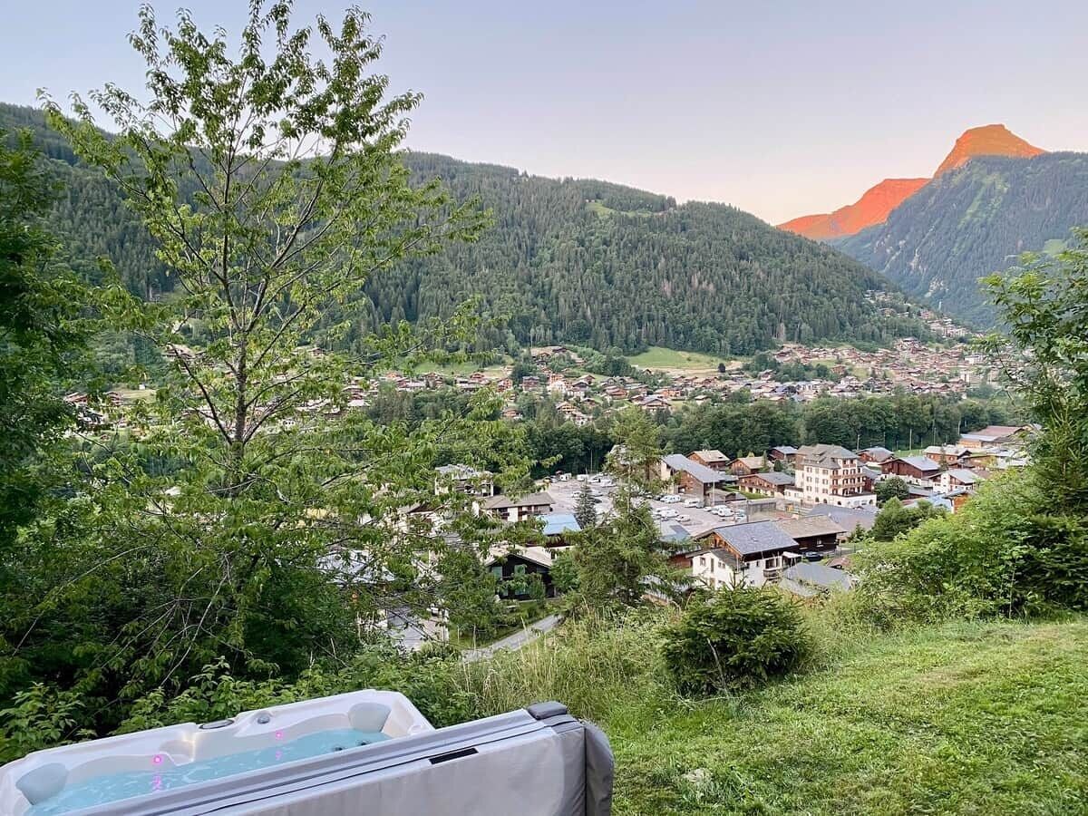 A mountainous landscape with a village, trees, and a pool area.