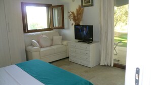 Une chambre à coucher avec un lit, un téléviseur posé sur une commode, une fenêtre et une vue sur l’extérieur.