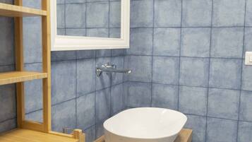 Un baño con un lavamanos blanco, estantes de madera y azulejos azules.
