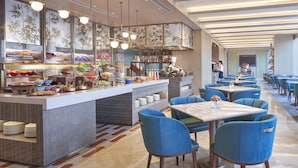 A modern restaurant with a buffet bar, blue upholstered chairs, and a long dining area. - Shangri-La Qiantan, Shanghai (Shanghai)