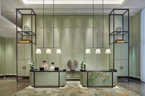 A hotel reception area with marble counters, pendant lighting, and a patterned carpet. - Shangri-La Qiantan, Shanghai (Shanghai)