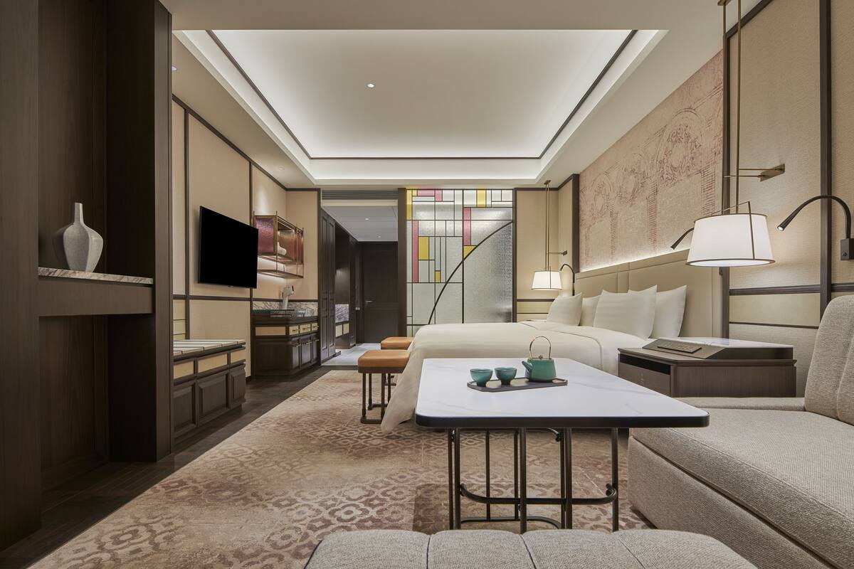 A modern hotel room with a skylight, a sofa, a small table, and a TV.