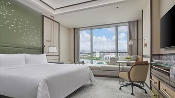 A hotel room with a large bed, a desk, a chair, and a TV.