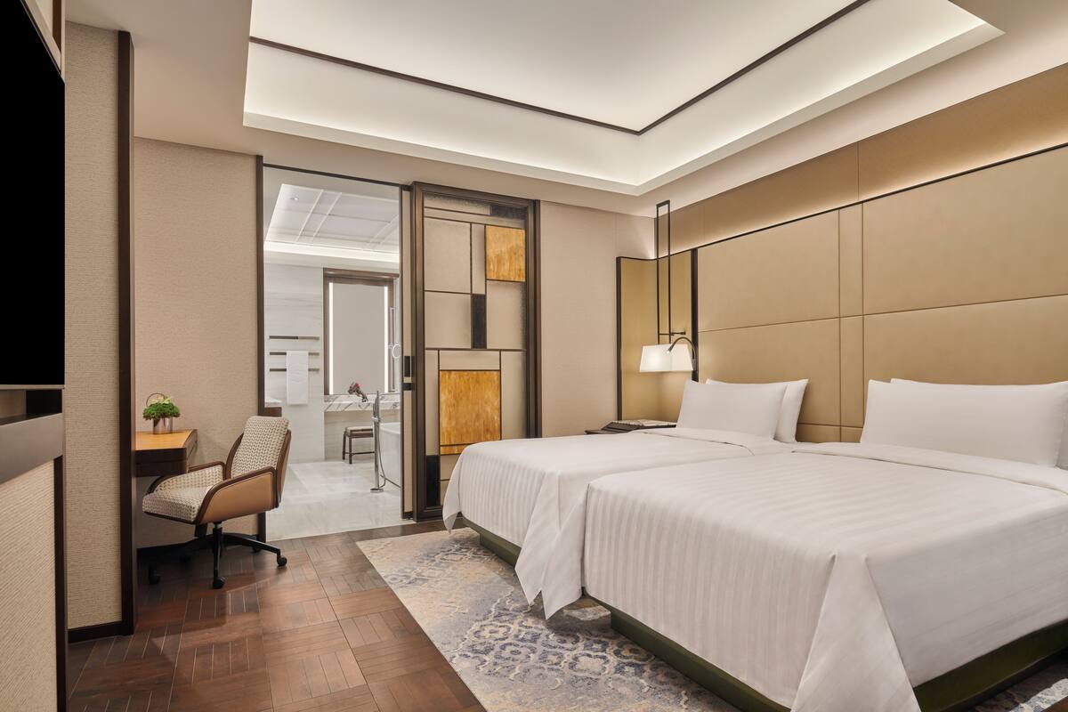 A hotel room with a large bed, a desk, and a chair.