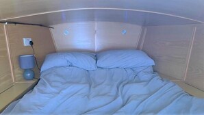 A compact, modern bedroom with a bunk bed, a bedside lamp, and a power outlet on the wall.