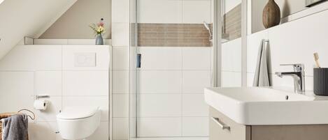 A modern bathroom with a shower, toilet, and sink.