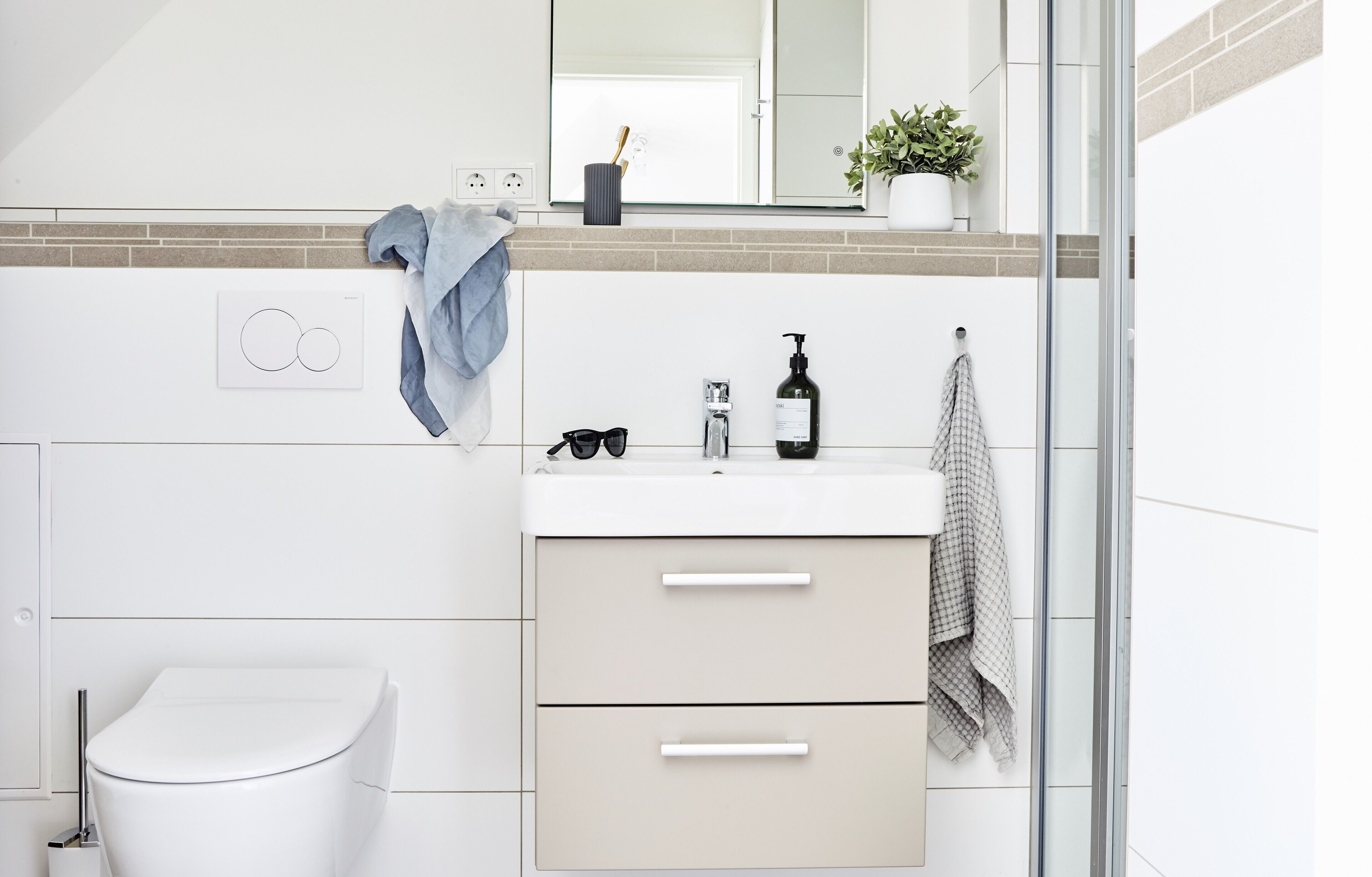 Un baño moderno con inodoro, lavamanos con espejo y zona de ducha.