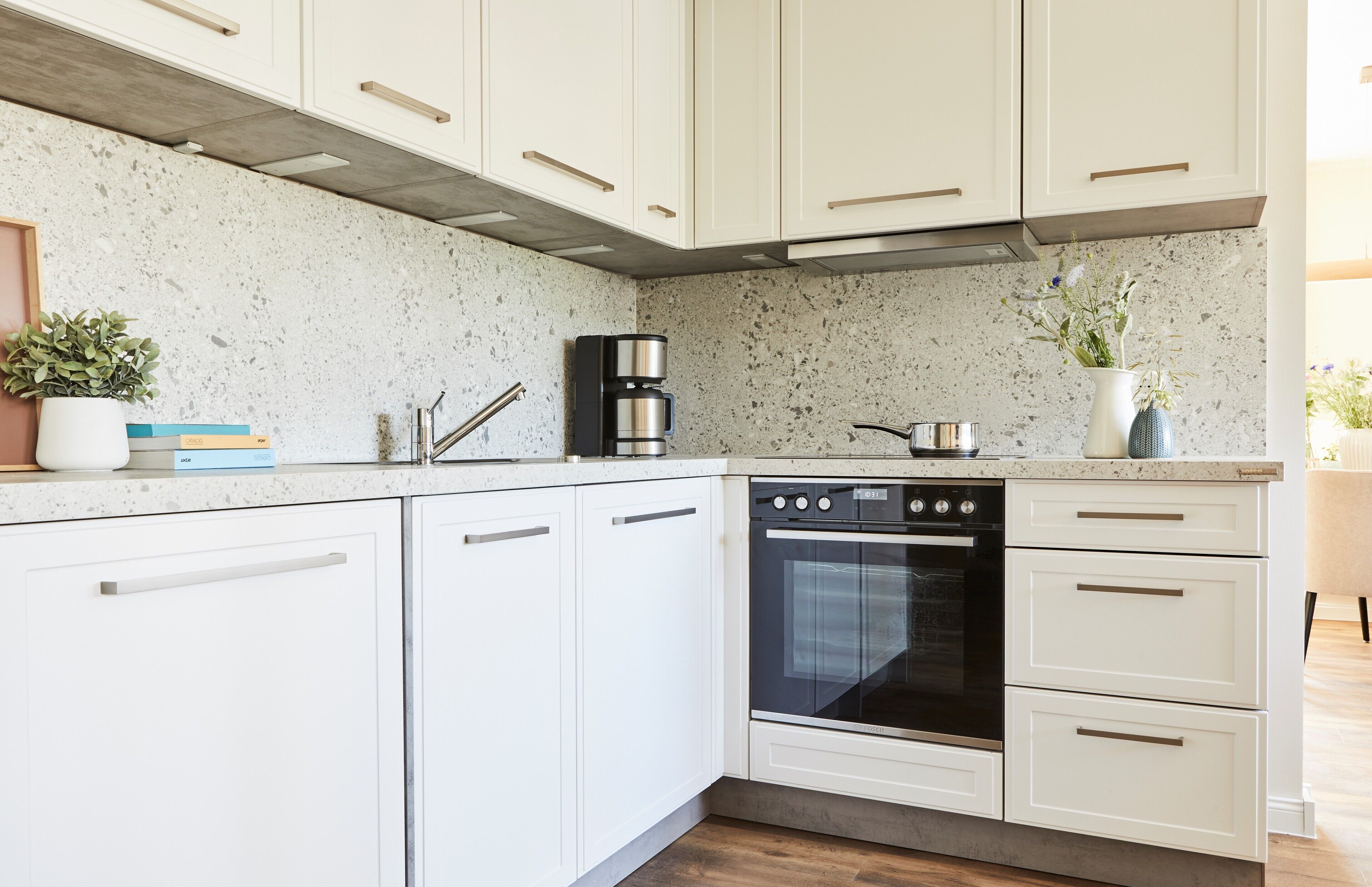 A kitchen with white cabinets, a built-in oven, and a coffee maker.