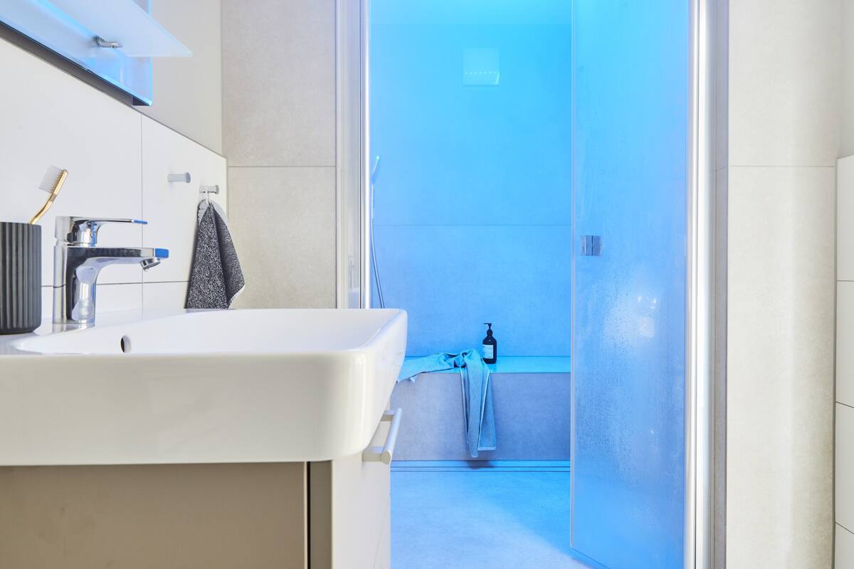 A modern bathroom with a white sink, a toothbrush holder, and a towel hanging on a rack.