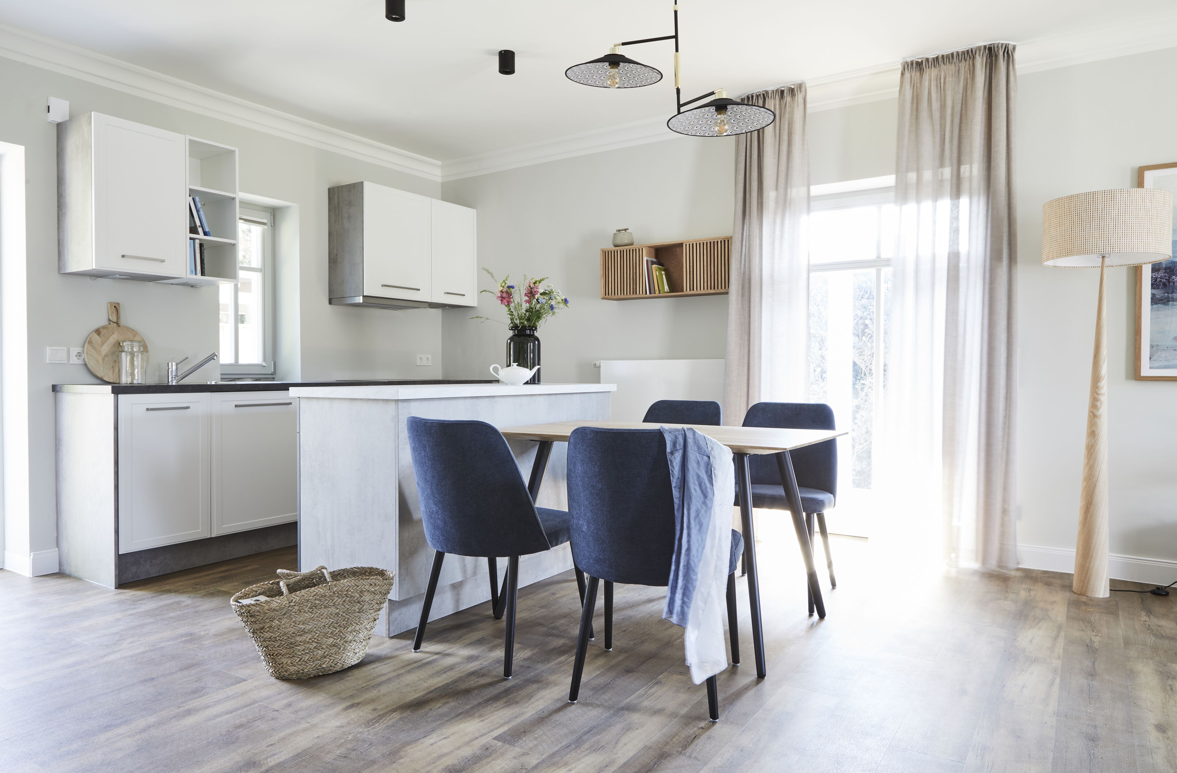 A modern kitchen with white cabinets, a central island, and a dining area with two chairs.