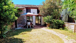 A patio area with a table and chairs, a stone pathway, and a building with a tiled roof. - The Plough House with 4 bedrooms (Saint-Just-Luzac)
