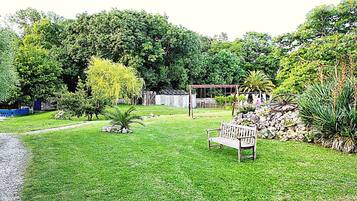 A well-maintained garden with a wooden bench, a gazebo, and various plants.