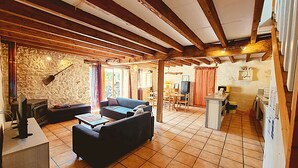 Una sala rústica con pared de piedra, vigas de madera, un sofá, una mesa de centro y una chimenea.