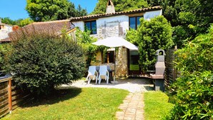A stone house with a tiled roof, a garden with a paved path, and a table with chairs outside. - La Mangeoire 2 bedroom gîte (Saint-Just-Luzac)