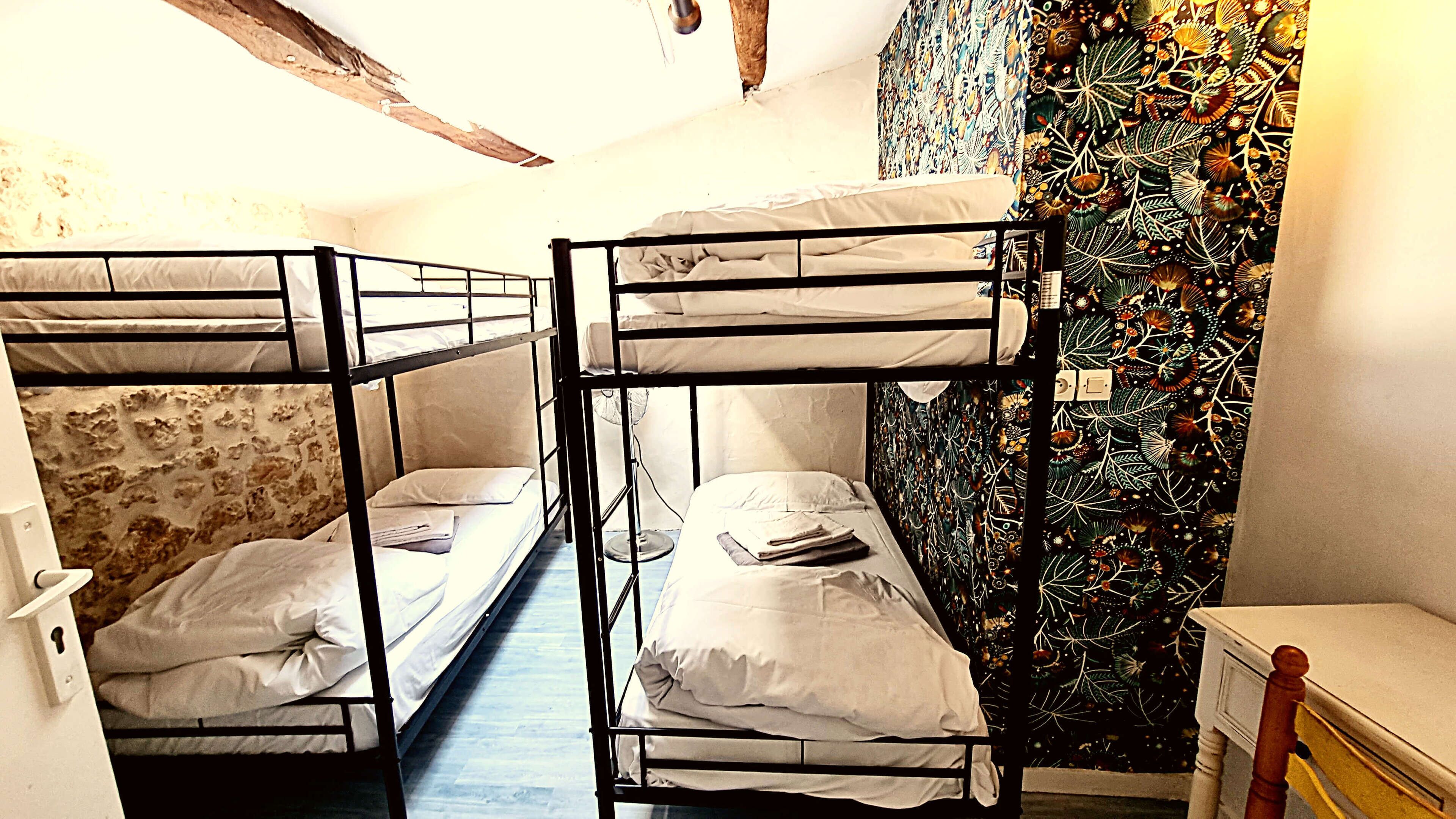 A room with bunk beds, a patterned wall, and a small wooden table.