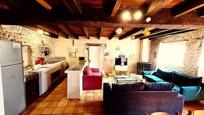 Une cuisine rustique dotée d’un four encastré, d’un lave-linge et d’un coin repas avec une table et des chaises.