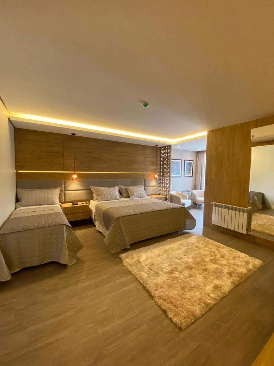 A modern bedroom with two beds, a large rug, and a wooden headboard.