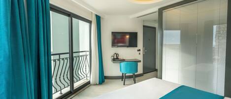 Una habitación de hotel con cama, escritorio, silla, televisor y puerta corrediza.
