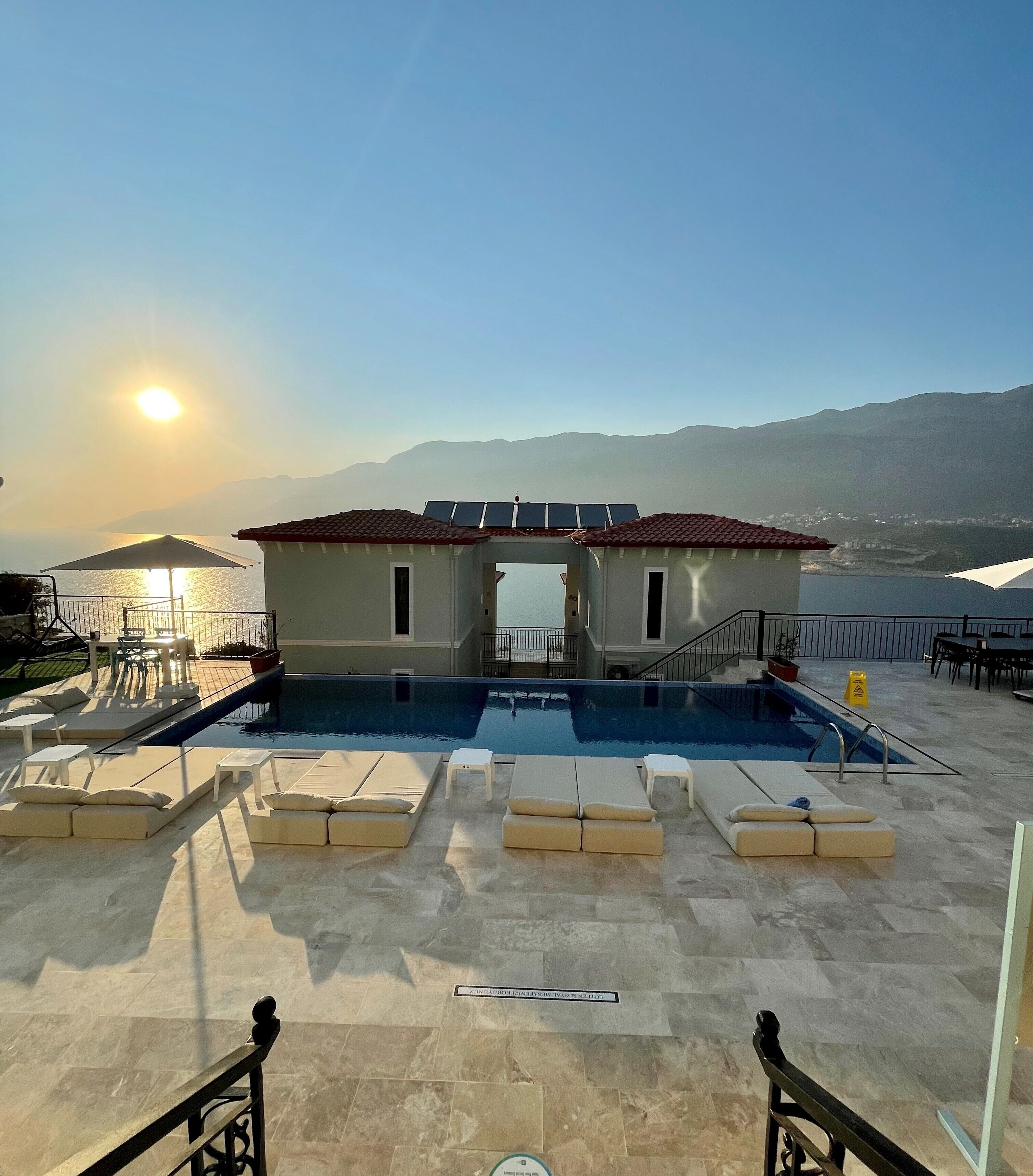 A rooftop pool area with lounge chairs and a view of the sea.