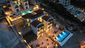 A multi-story hotel with a swimming pool, outdoor seating, and a staircase leading to the upper floors. - GÜMÜŞ YAZAR  HOTEL (Kas)