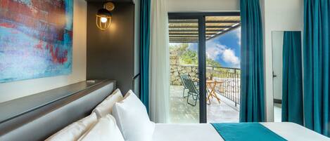 A hotel room with a large bed, a view of the outdoor patio, and a colorful abstract painting on the wall.