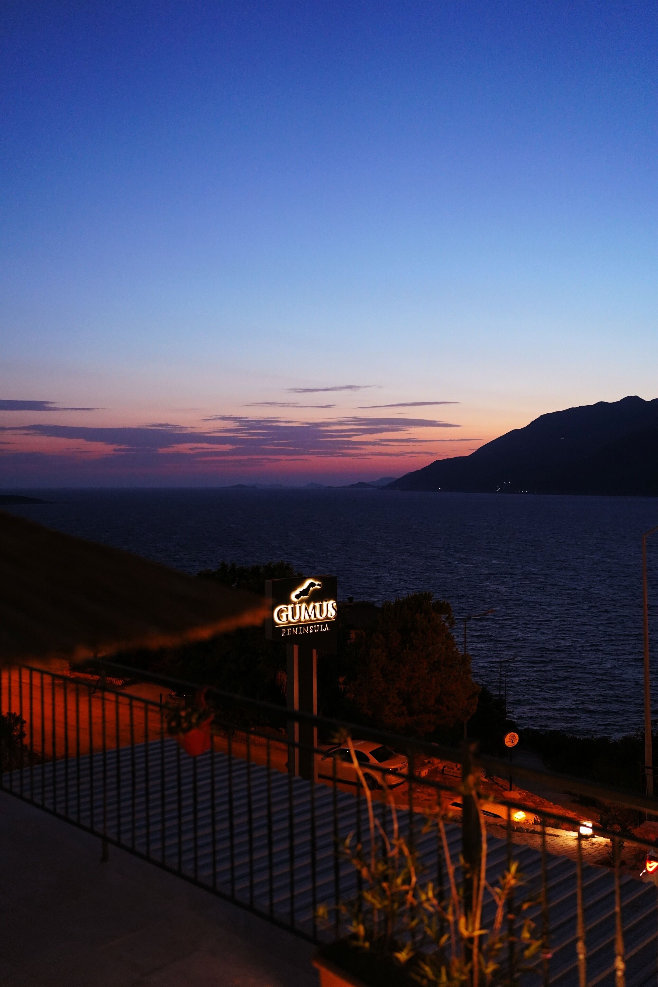 A coastal view at dusk with a sign for "GUMUS PENINSULA."
