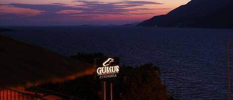 A coastal view at dusk with a sign for "GUMUS PENINSULA."