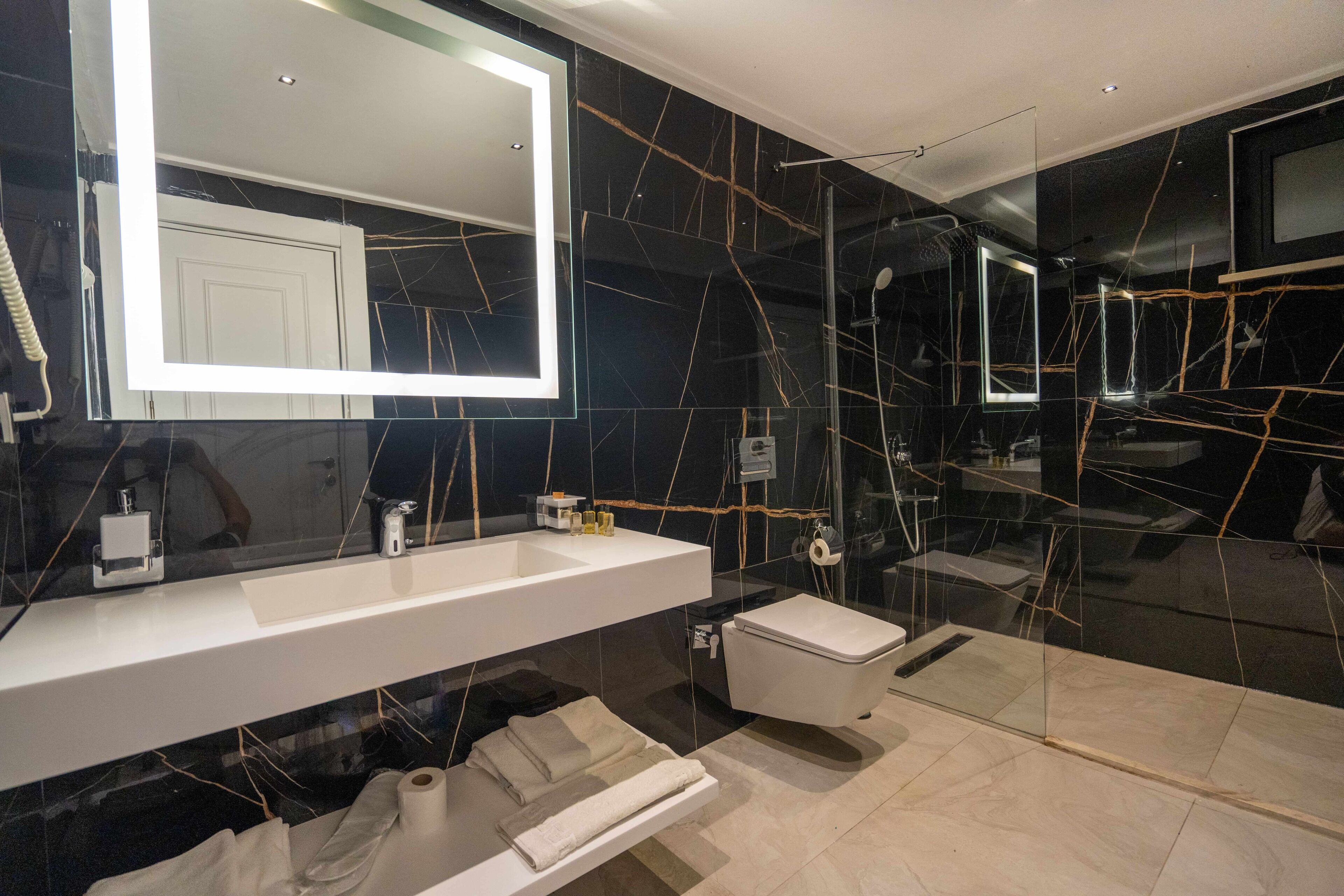 A modern bathroom with a large mirror, white vanity, and a glass-enclosed shower area.