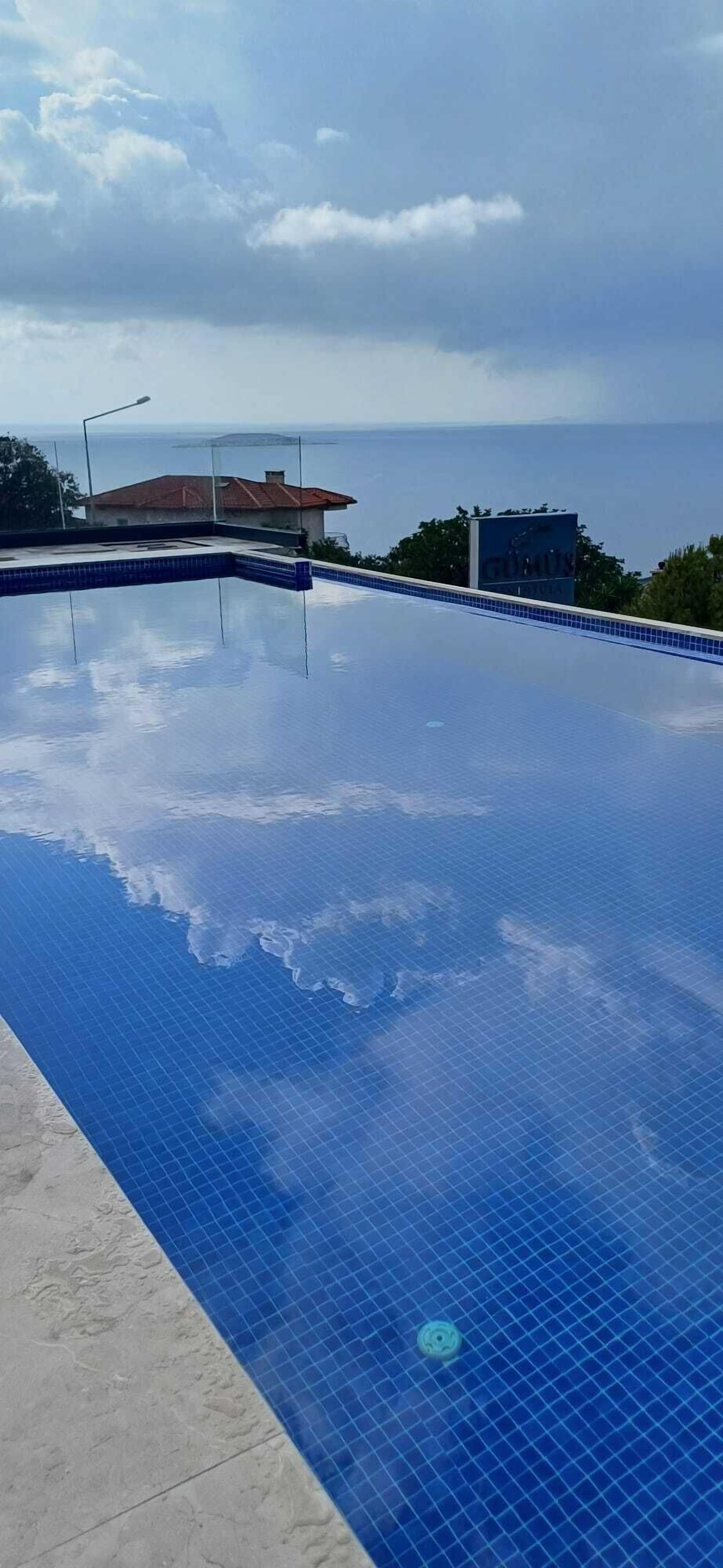 A clear blue swimming pool with a tiled edge, surrounded by a concrete deck.