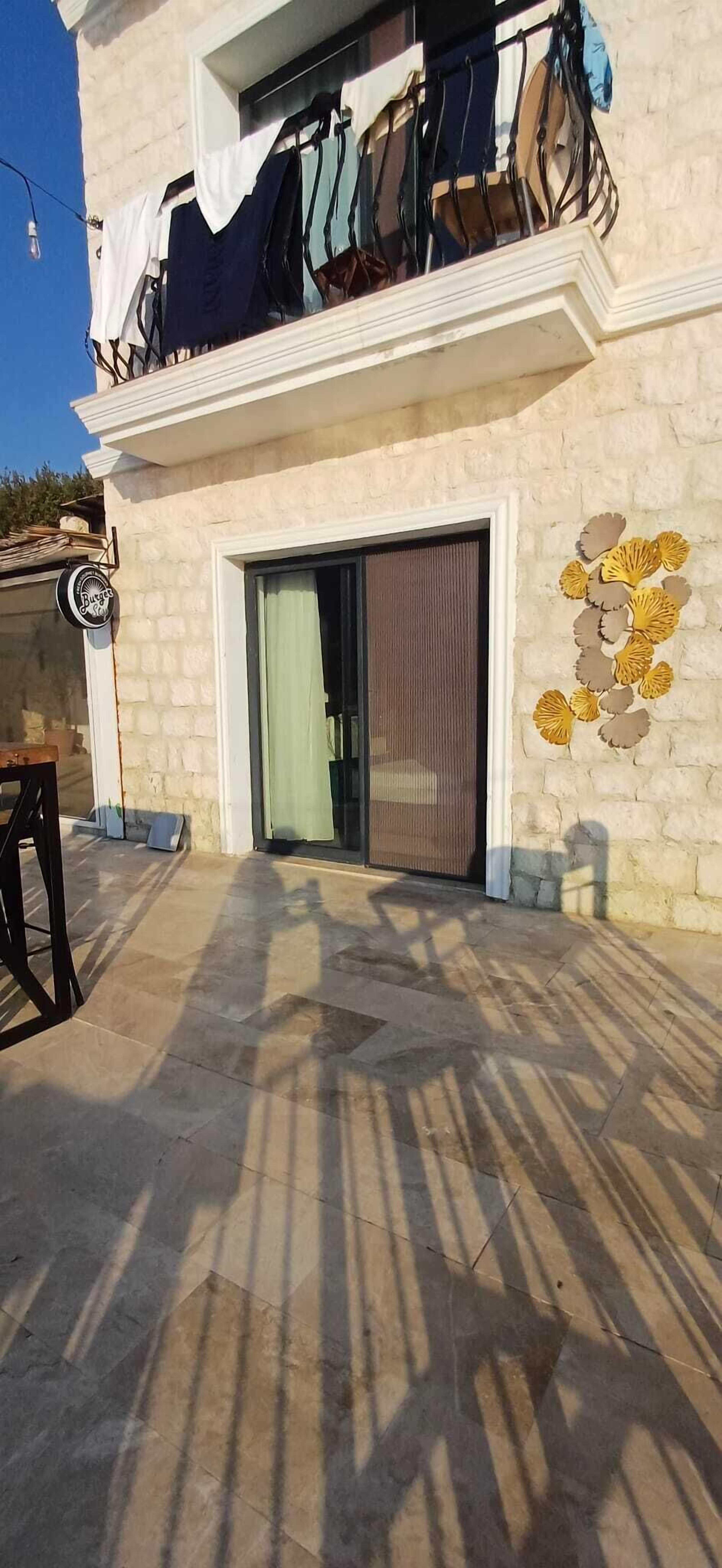 Un edificio con balcón, una puerta con panel de vidrio y una pared de piedra con detalles decorativos.