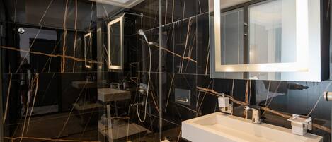 Un baño moderno con ducha envuelta en vidrio, un lavabo blanco y un espejo grande.