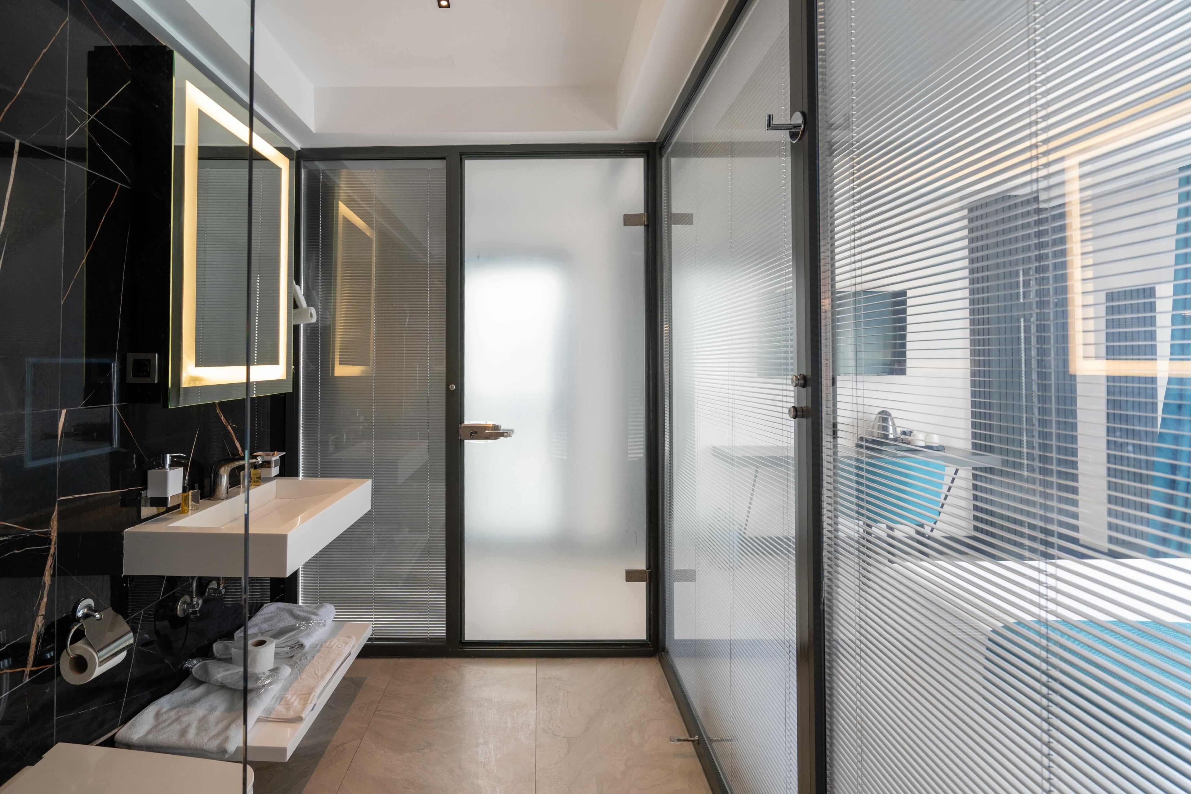 Un baño moderno con puerta de vidrio, lavamanos blanco y espejo.