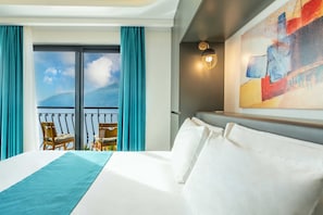A hotel room with a large bed, a view of the sea through a balcony, and a modern abstract painting on the wall. - GÜMÜŞ YAZAR HOTEL (Kas)